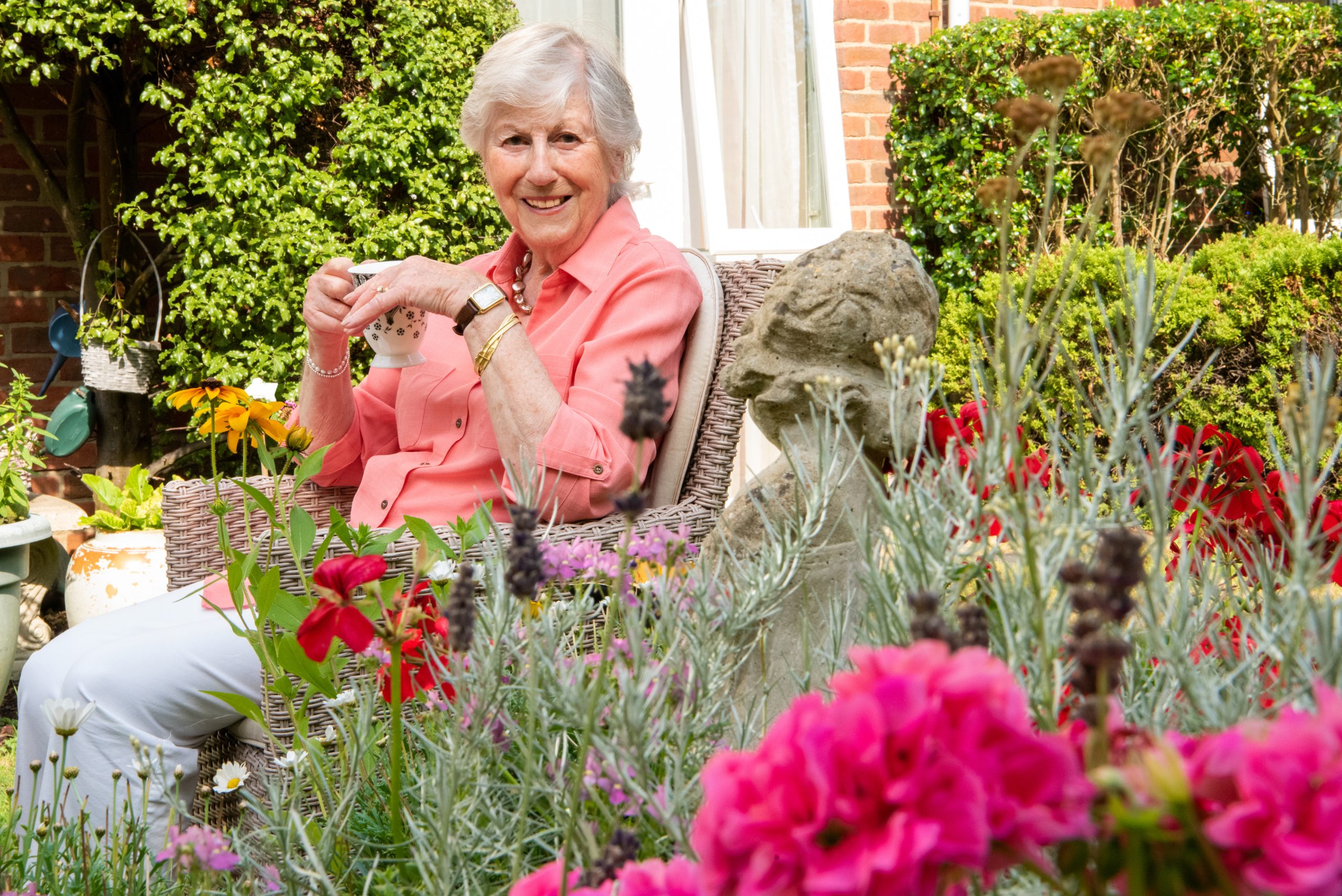 Knightwood resident in garden with cup of tea